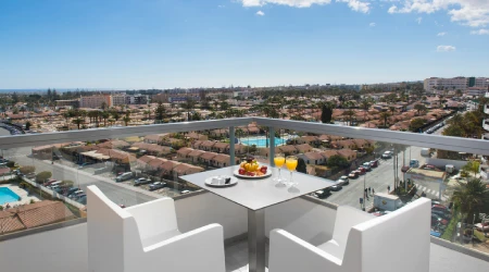 Terraza con mesas y vista panor&aacute;mica de la ciudad y alberca.