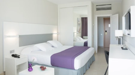 Dormitorio moderno con cama doble y mesa auxiliar blanca con l&aacute;mparas.
