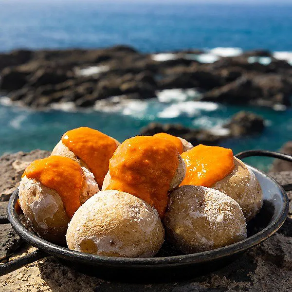 Bol de bu&ntilde;uelos fritos y rojos sobre rocas junto al mar