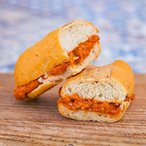 Pan con salsa roja, trozo abierto sobre tabla de madera