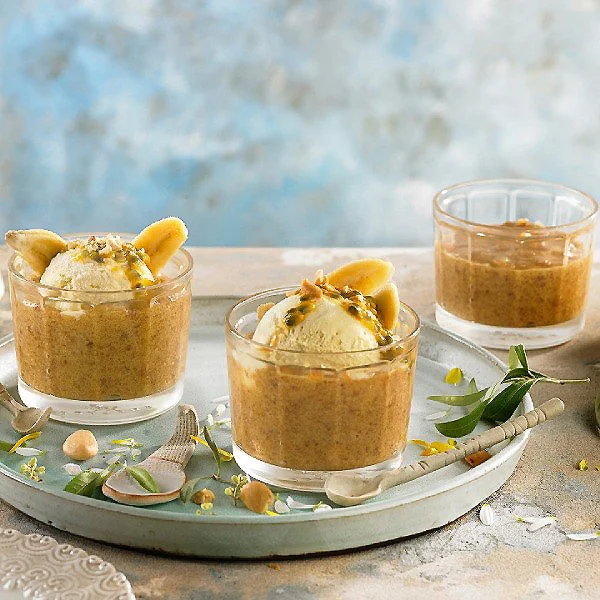 Vasitos de crema de frutos secos con pasas y banana, en bandeja.