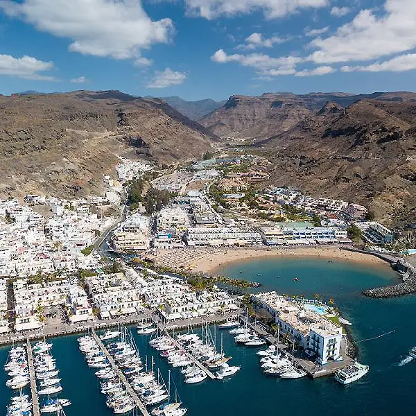 Vista a&eacute;rea de un puerto deportivo con un pueblo y playa en la bah&iacute;a