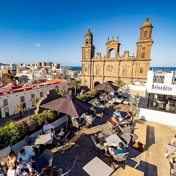 Terraza con mesas y vista de una iglesia colonial junto al mar.