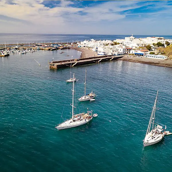 Yates en un puerto junto a edificios blancos y muelle sobre el mar