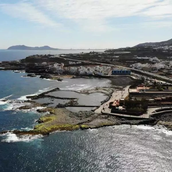 Vista a&eacute;rea de una costa con urbanizaci&oacute;n, playa y muelles junto al mar