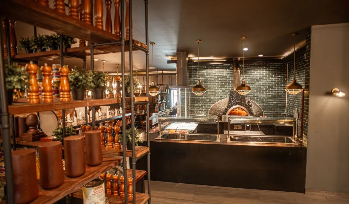 Cocina de restaurante con horno de pizza y barra con especias y utensilios.