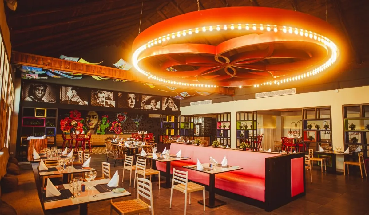 Restaurante interior con mesas y barra bajo una l&aacute;mpara circular LED.