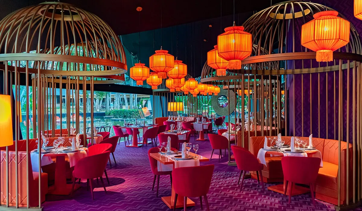 Comedor elegante con mesas rojas y l&aacute;mparas colgantes en jaulas decorativas