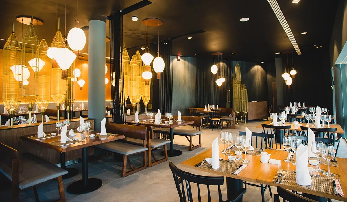 Sal&oacute;n elegante con mesas puestas y candelabros colgantes de estilo moderno.