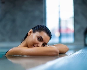 Mujer recostada con sonrisa en una piscina o spa.