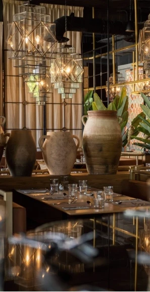 Jarrones de cer&aacute;mica y luces decorativas en un comedor con vidrio y metal.