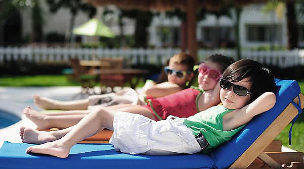 Ni&ntilde;os jugando en la piscina con flotadores y gafas de sol, al aire libre