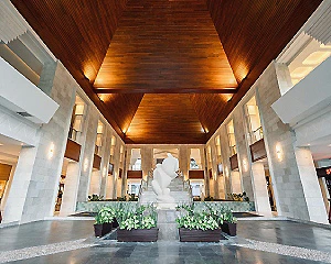 Pasillo interior de hotel con plantas y techo de madera iluminado