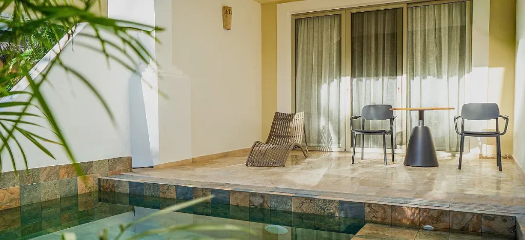 Terraza con piscina peque&ntilde;a, dos sillas y cortinas en grandes puertas correderas