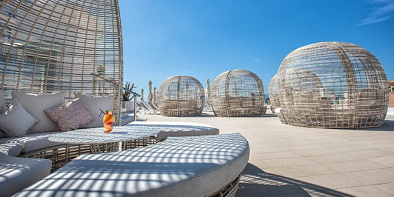 Terraza con sof&aacute;s y c&uacute;pulas de malla esf&eacute;ricas bajo cielo despejado.
