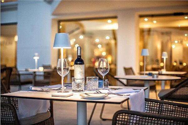 Mesa de restaurante con vino, copas y velas en un ambiente iluminado