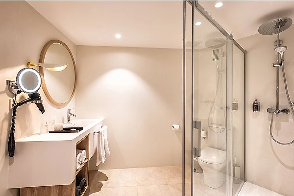 Ba&ntilde;o moderno con ducha de vidrio, lavabo y espejo con luz circular