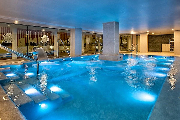 Piscina interior con luces y chorros, en un spa nocturno