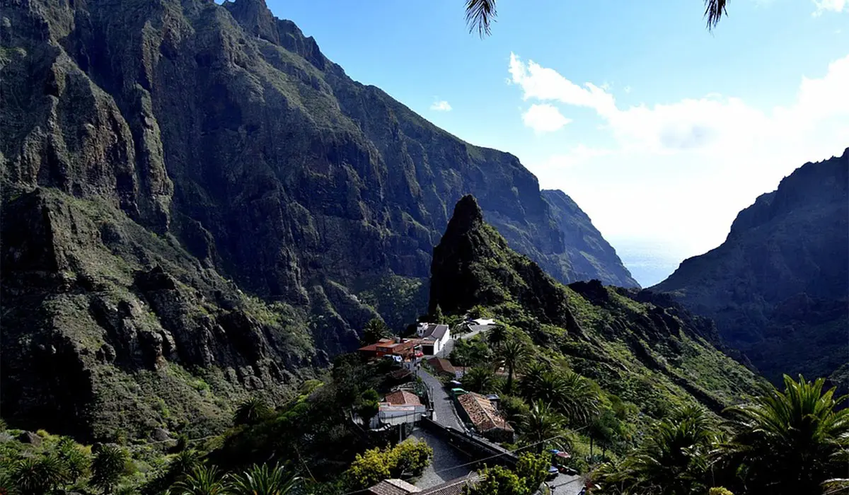 Pueblo tropical entre monta&ntilde;as y palmeras, valle con cielo despejado