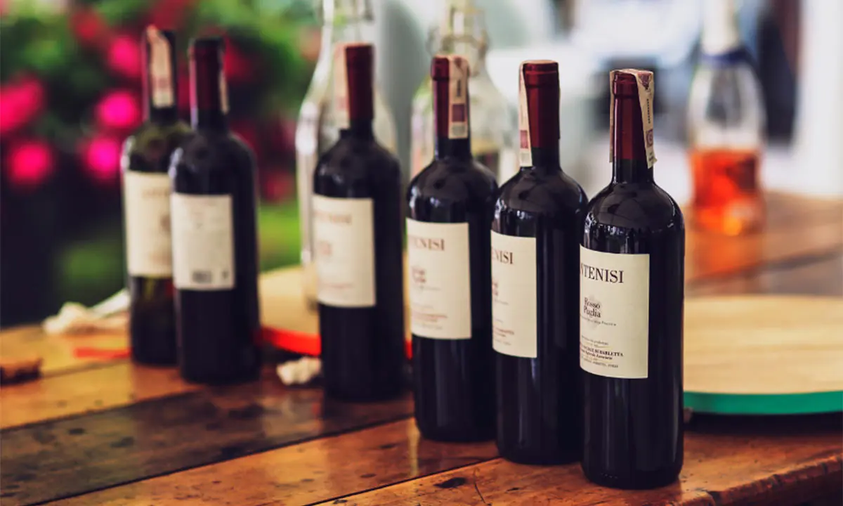 Botellas de vino tinto sobre mesa de madera, fondo desenfocado con luces rojas
