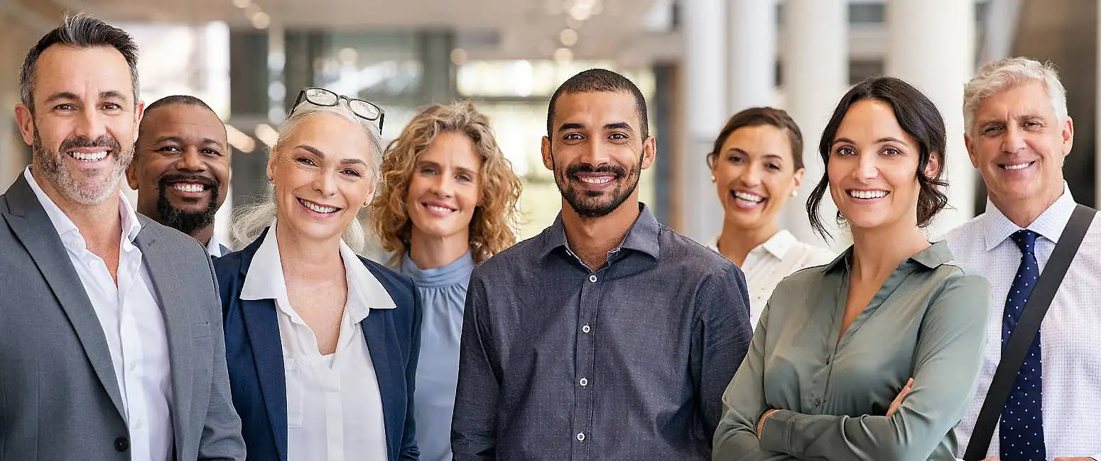 Equipo diverso de profesionales sonrientes en oficina, posando para foto grupal