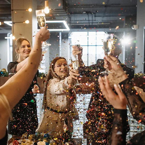 Celebraci&oacute;n en un restaurante, gente brindando con copas entre confeti.