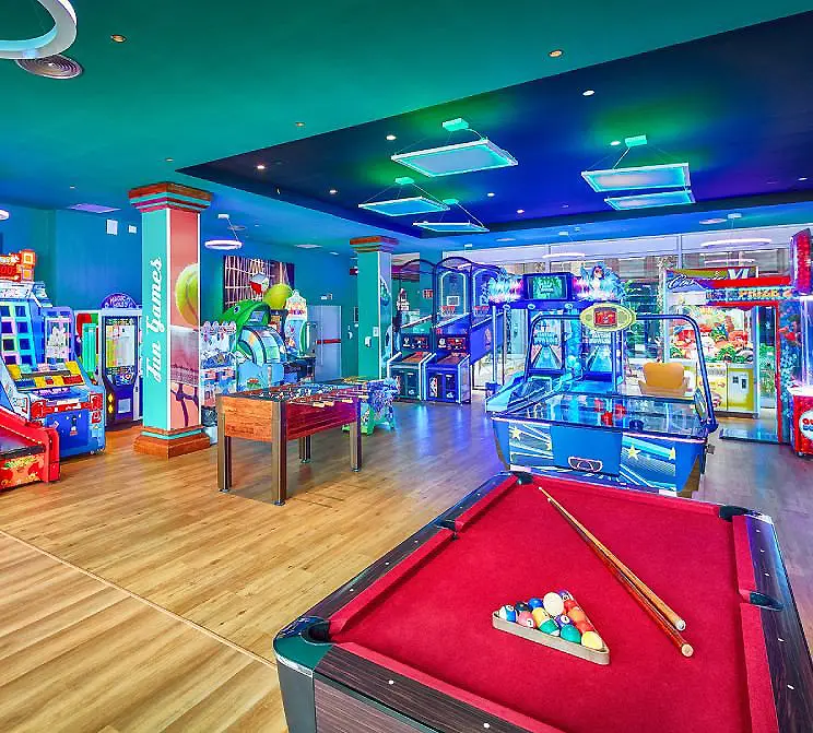 Sala de juegos infantil con billar, m&aacute;quinas arcade y boleras con luces LED.