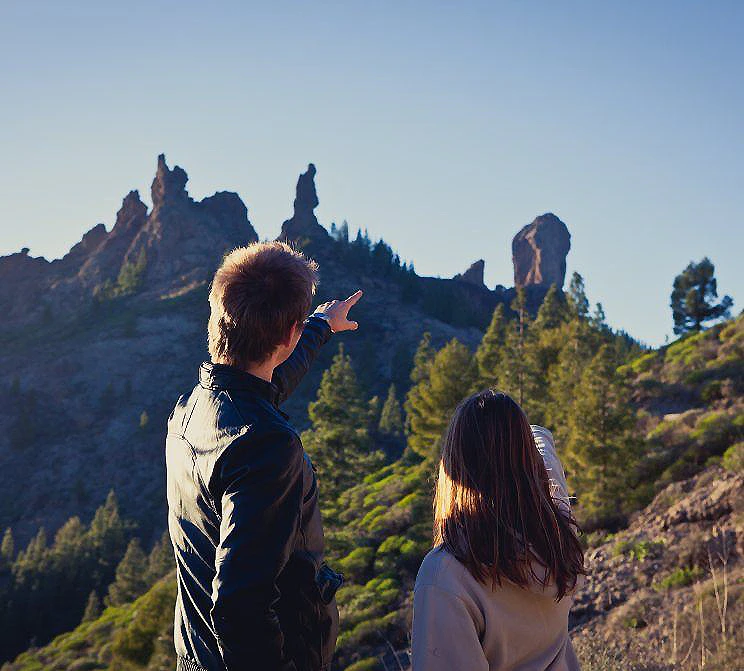Dos personas contemplando monta&ntilde;as y un paisaje al atardecer