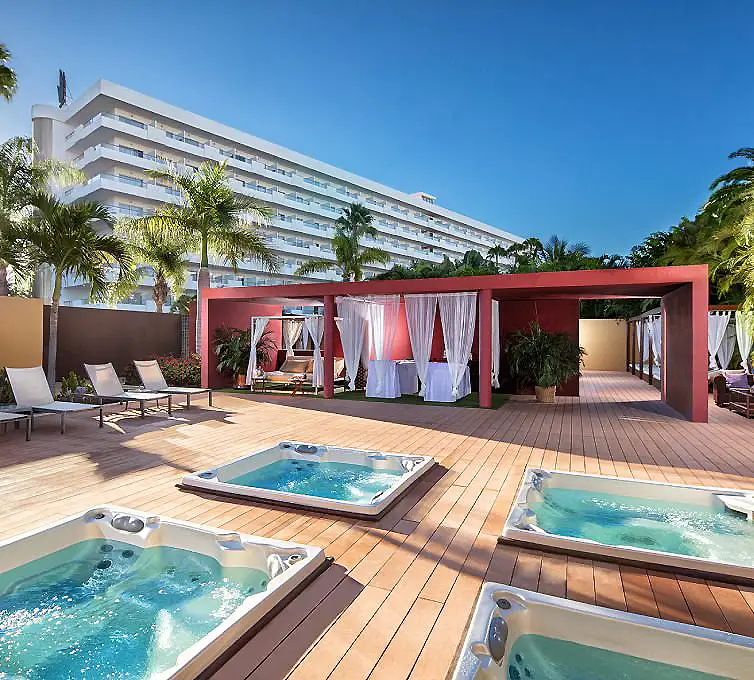 Terraza de hotel con jacuzzi y piscina, palmeras y caba&ntilde;a roja al aire libre
