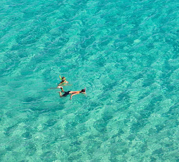 Persona nadando en aguas turquesa, vista desde arriba.