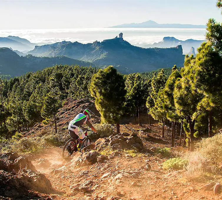 Ciclista en bicicleta de monta&ntilde;a por sendero entre monta&ntilde;as y niebla