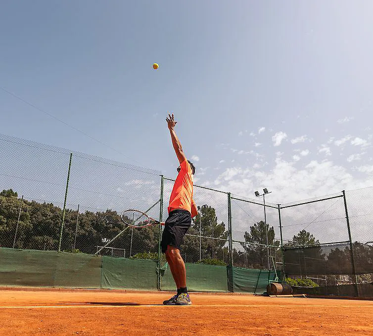 Jugador de p&aacute;del lanzando una pelota al aire en una cancha al aire libre