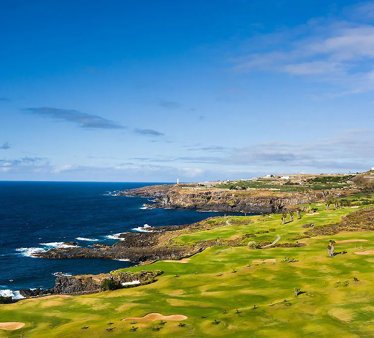 Campo de golf junto al oc&eacute;ano, acantilados y cielo azul al atardecer