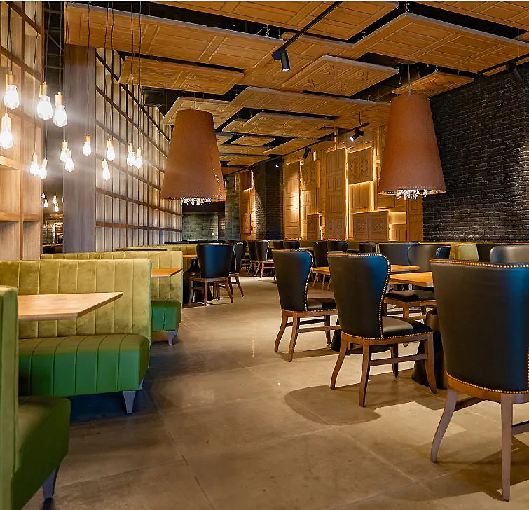 Interior de restaurante con mesas, sillas y l&aacute;mparas colgantes en luz c&aacute;lida