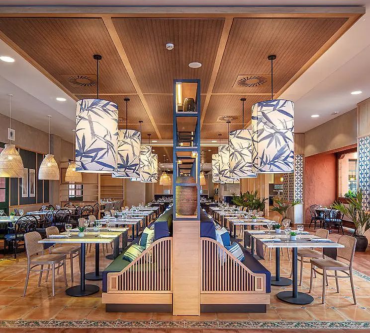 Restaurante con mesas, sillas y l&aacute;mparas, decoraci&oacute;n azul y madera.