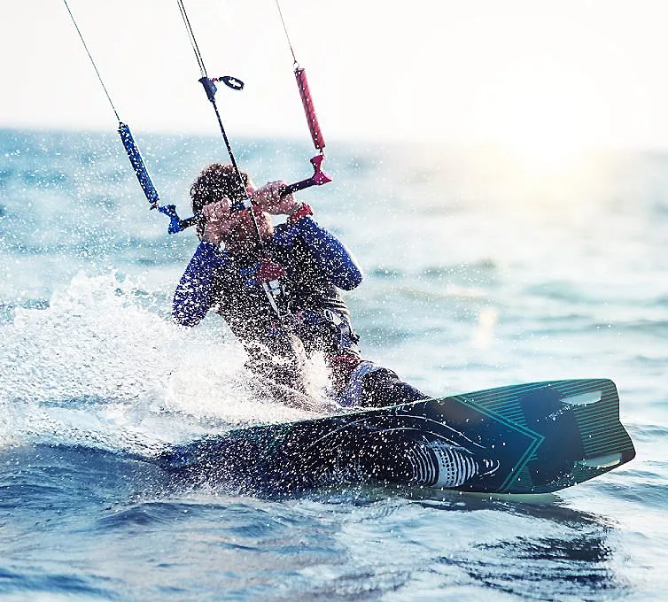 Kitesurfista salta sobre el agua con cometa en fuerte viento.
