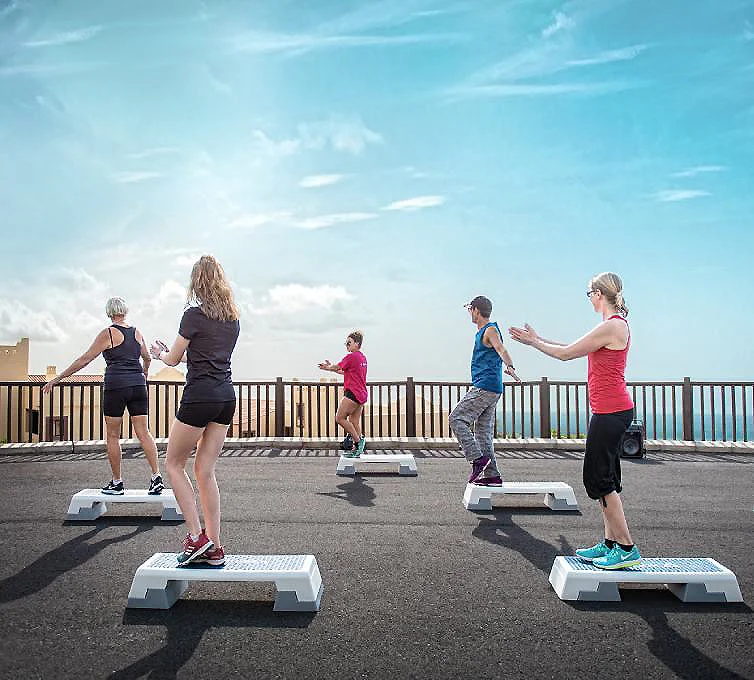 Personas entrenando en escalones de ejercicio al aire libre junto al mar