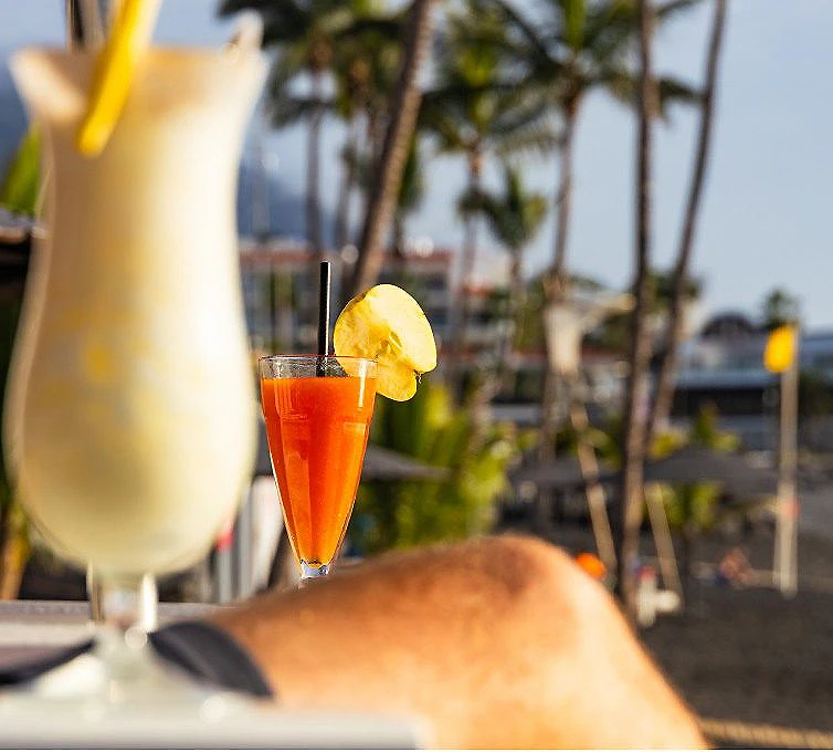 C&oacute;ctel naranja en vaso con rodaja de pi&ntilde;a y sombrilla, vista tropical.