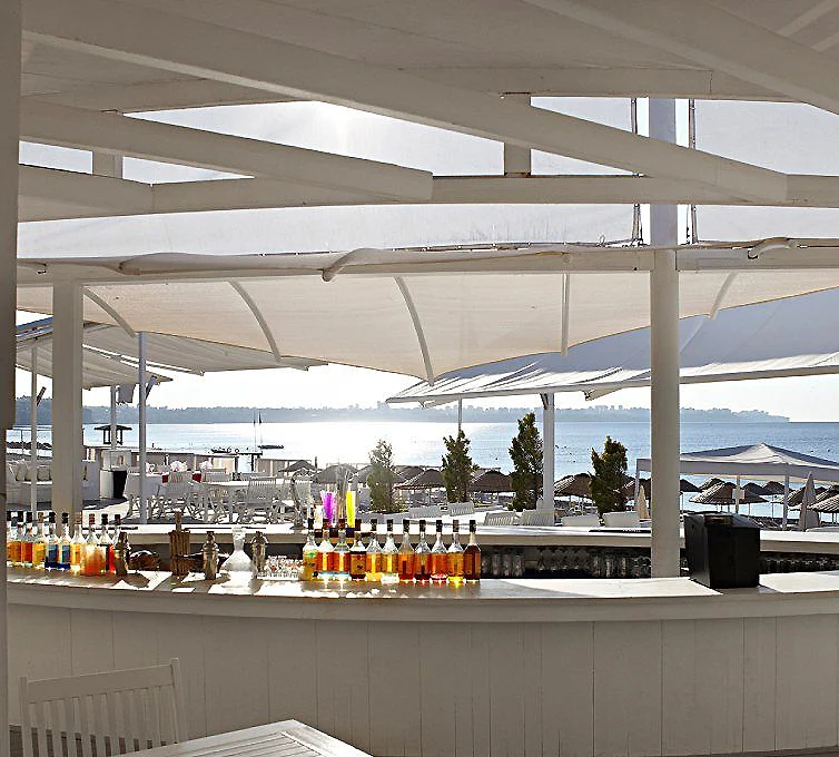 Barra de bebidas con botellas de colores bajo carpas, junto al mar