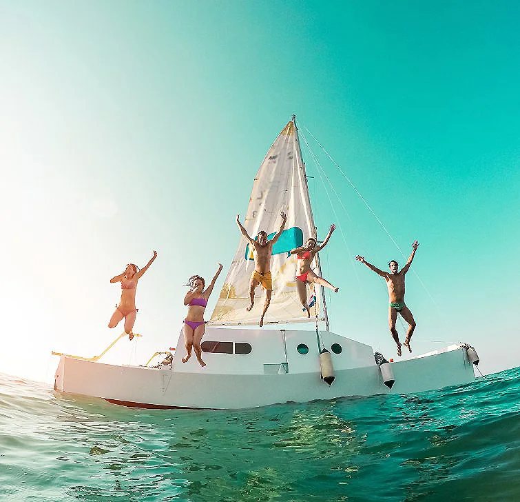 Personas saltando desde un catamar&aacute;n sobre el mar bajo el sol