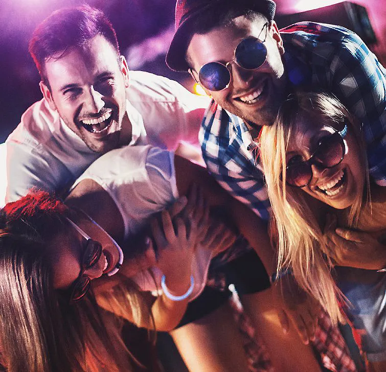 Grupo de amigos sonrientes celebrando con confeti y sombreros en fiesta.
