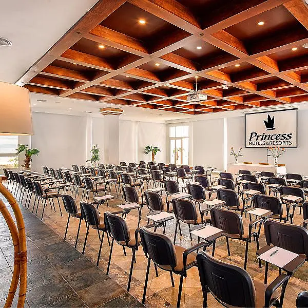 Sala de conferencias con mesas y sillas, techo de madera y logotipo Princess