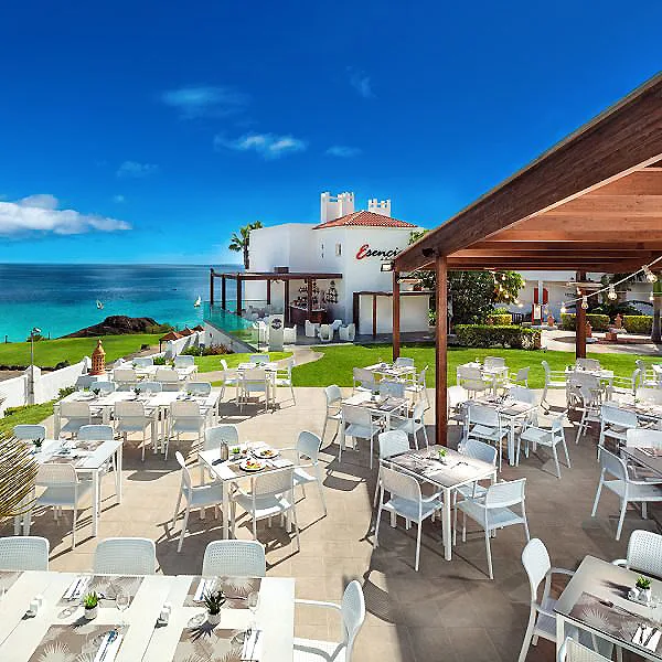 Terraza de restaurante con mesas blancas y vista al mar azul