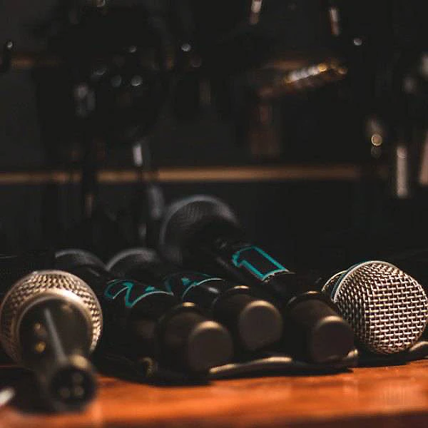 Micr&oacute;fonos sobre una mesa en un estudio, con luces tenue al fondo