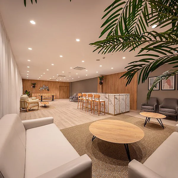 Sala moderna con sof&aacute; blanco, mesa redonda y barra con bancos en madera.