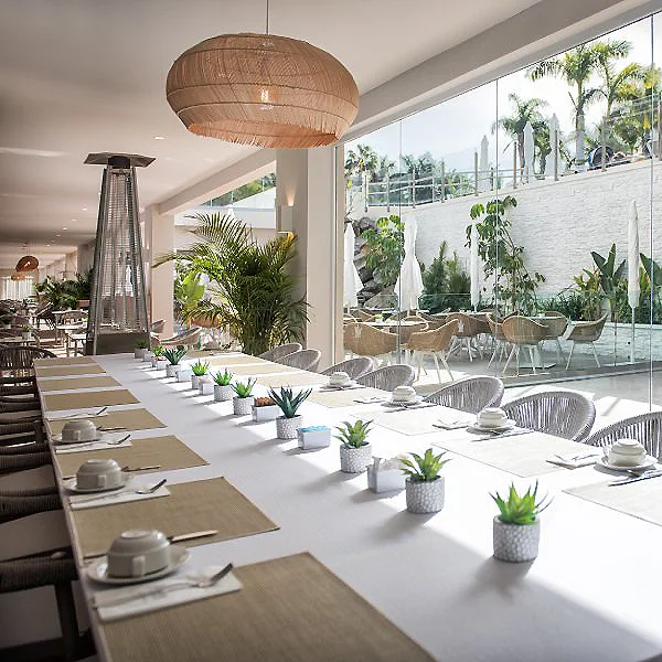 Comedor exterior con mesa larga, macetas y chimenea bajo techo y techo de luz