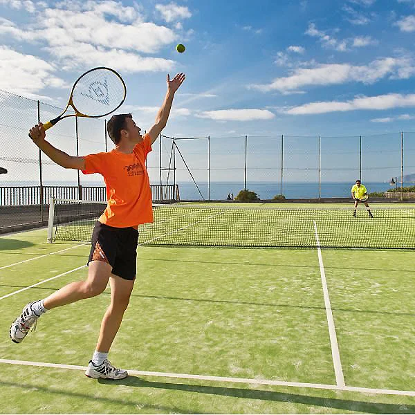 Jugador de p&aacute;del lanzando una pelota en una pista al aire libre junto al mar