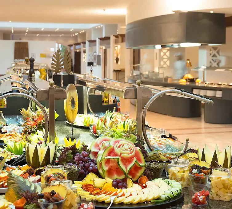 Mesa buffet con frutas y verduras, en un restaurante moderno.
