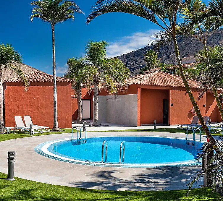 Piscina azul con palmeras y casas de color rojo bajo cielo despejado