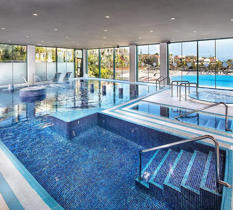 Piscina cubierta moderna con camas de hidromasaje y ventanas panor&aacute;micas.